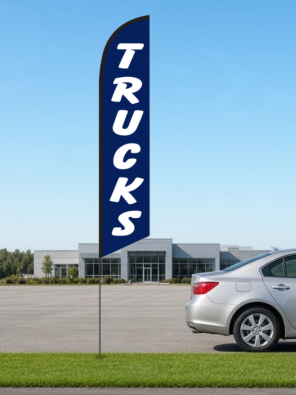 Trucks swooper feather flag, white TRUCKS lettering on navy blue, black pole sleeve, on a pole in the grass strip of a dealership lot beside a silver sedan